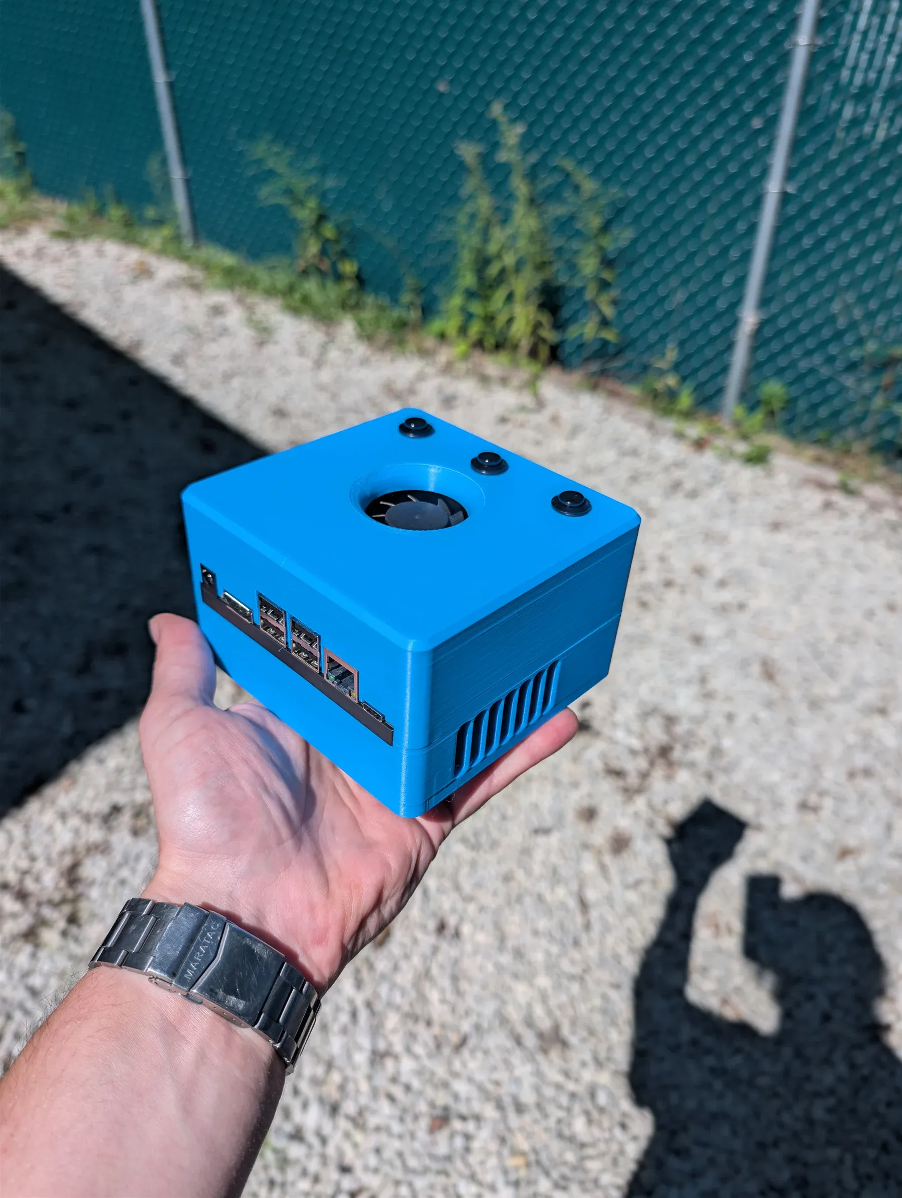 The finished 3D-printed Jetson case held in one hand, with the fan and computer ports visible.
